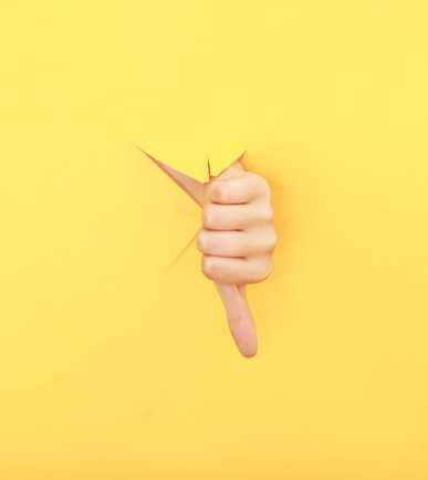 Ein Daumen nach unten vor gelbem Hintergrund als Symbol der Kritik an den Entlassungen der Post